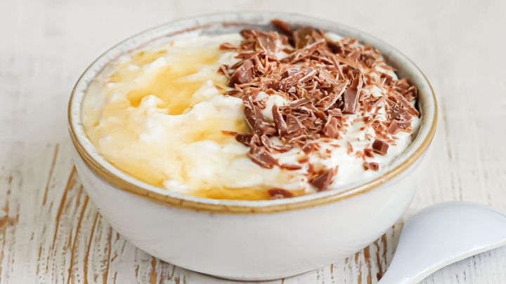 Eine Sch&uuml;ssel mit cremigem Dessert, &uuml;berzogen mit Schokoladensp&auml;nen, steht auf einem rustikalen Holzuntergrund.