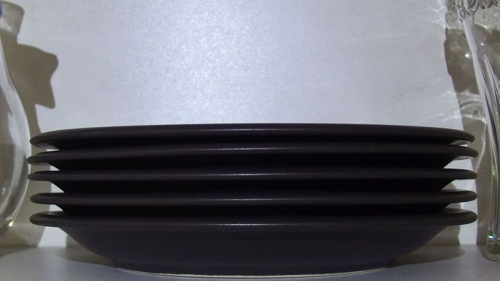 Schwarze Teller sind ordentlich gestapelt im K&uuml;chenschrank, neben Gl&auml;sern, die f&uuml;r mehr Platz in der K&uuml;che sorgen.