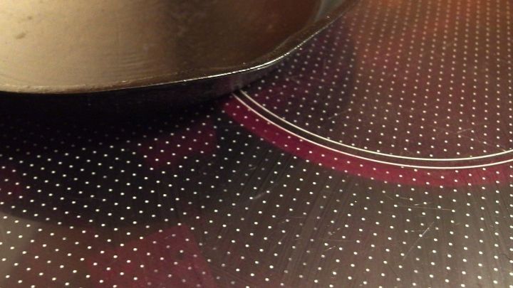 Ein gl&auml;nzendes Glaskeramikfeld zeigt eine schwarze Pfanne, die auf der Oberfl&auml;che steht, mit sichtbaren Kochstellen in einem modernen K&uuml;chenumfeld.