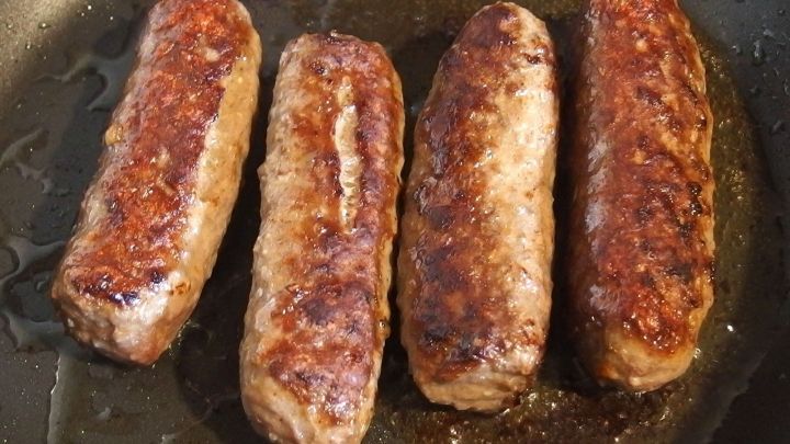 Cevapcici braten in einer Pfanne, gleichm&auml;&szlig;ig goldbraun gebr&auml;unt, bereit zum Servieren in einer klassischen K&uuml;che.