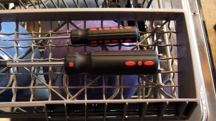 Zwei schwarze Schraubendreher liegen in einem Geschirrkorb, w&auml;hrend sie gereinigt werden. Die Umgebung zeigt einen Geschirrsp&uuml;ler.