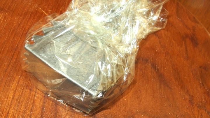 Ein Fleischklopfer ist in Frischhaltefolie eingewickelt und liegt auf einer Holzoberfl&auml;che, um sauber zu bleiben.