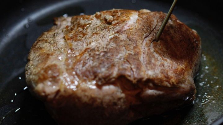 Ein Braten liegt in einer Pfanne, w&auml;hrend ein Thermometer darin steckt, um die Garheit zu &uuml;berpr&uuml;fen.