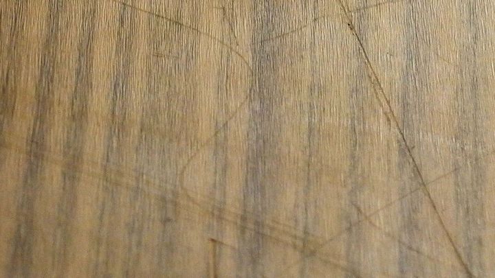 Ein Holzm&ouml;belst&uuml;ck zeigt mehrere Kratzer, die durch Gebrauchsspuren entstanden sind, in einem wohnlichen Raum.