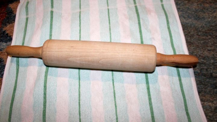 Ein Holztaisenroller liegt auf einem gestreiften K&uuml;chentuch, bereit zum Ausrollen von Teig gegen Mandelentz&uuml;ndung und Halsschmerzen.