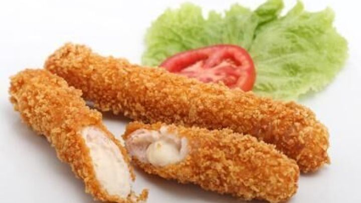 Mozzarellasticks liegen auf einem Teller, einer ist aufgebrochen. Im Hintergrund sind ein Salatblatt und eine Tomatenscheibe.