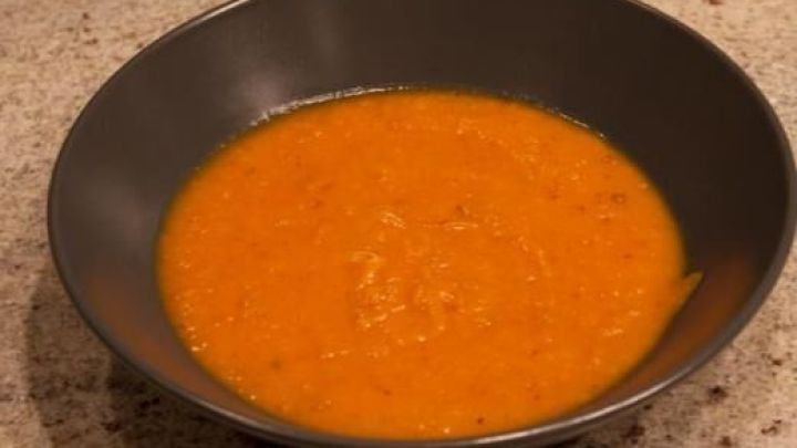 Eine orangefarbene Suppe in einer schwarzen Sch&uuml;ssel vermittelt den Eindruck von gef&auml;lschter K&uuml;rbissuppe, die aromatisch aussieht.