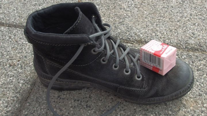 Ein schwarzer Schuh steht auf dem Boden, w&auml;hrend ein P&auml;ckchen Hefe oben darauf platziert ist, um Fu&szlig;pilz zu behandeln.