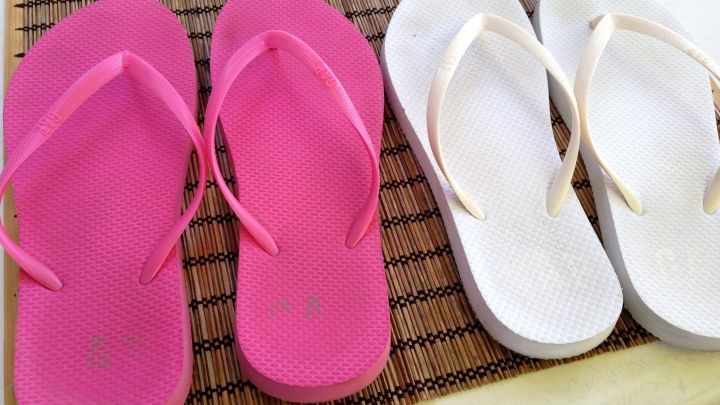 Rosa und wei&szlig;e Flip-Flops liegen nebeneinander auf einem Tisch, bereit, mit Gardinenwaschmittel gereinigt zu werden.