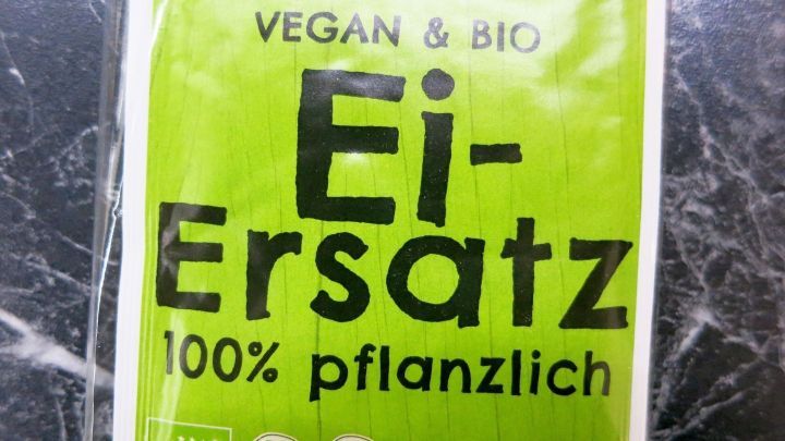 Ein Paket mit gr&uuml;nem Etikett zeigt "Ei-Ersatz" und betont, dass es 100% pflanzlich und vegan ist.