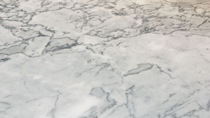 Eine gl&auml;nzende Marmoroberfl&auml;che zeigt leichte S&auml;uresch&auml;den, die auf eine bevorstehende Reparatur mit Nassschleifpapier hinweisen.