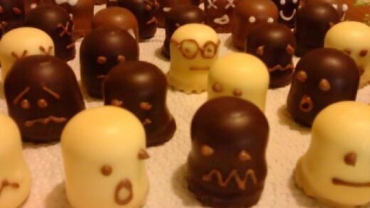 Schokok&uuml;sse dekoriert als Geister mit Gesichtsz&uuml;gen stehen auf wei&szlig;em Tuch, ideal als Halloween-Gimmicks.