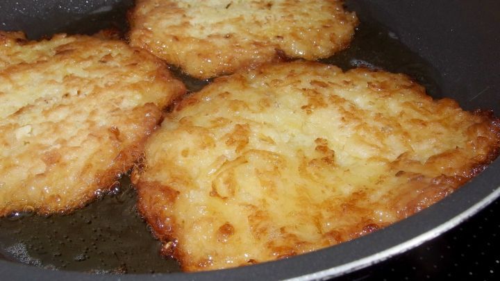 Krosse Quarkkartoffelpuffer braten in einer Pfanne, umgeben von hei&szlig;em &Ouml;l, goldbraun und appetitlich.