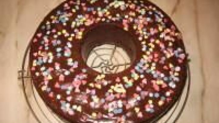 Ein Bananenkuchen mit Schokostreuseln steht auf einem Kuchengitter. Er hat eine bunten Streusel-Dekoration und ist rund.