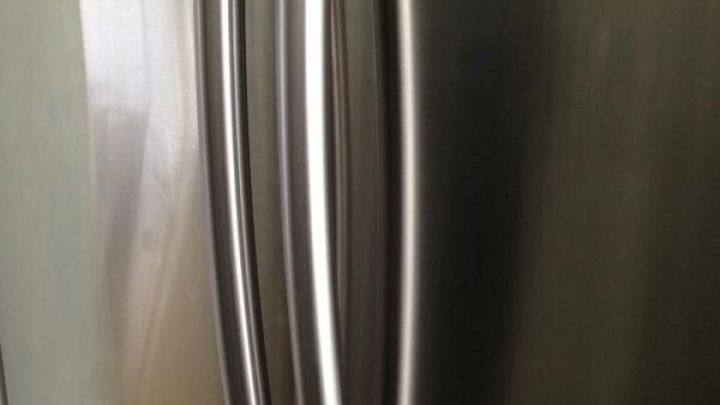 Edelstahlk&uuml;hlschrank zeigt seinen gl&auml;nzenden T&uuml;rgriff in einer modernen K&uuml;che ohne sichtbare Verschmutzungen.