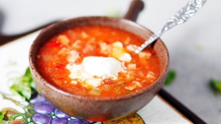 In einer schalenf&ouml;rmigen Sch&uuml;ssel liegt eine dampfende Hochzeitssoljanka mit Sahne, umgeben von einem bunten Teller.