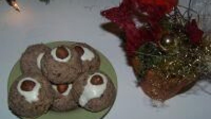 Zimtkugeln liegen auf einem Teller, dekoriert mit Haseln&uuml;ssen, neben weihnachtlichem Tischschmuck mit roten Sternen.