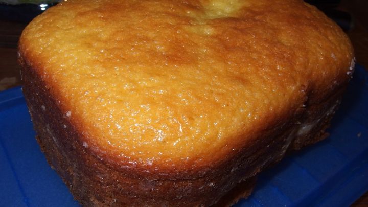 Ein frisch gebackener Sandkuchen liegt auf einem blauen Untergrund und strahlt eine goldbraune, knusprige Oberfl&auml;che aus.