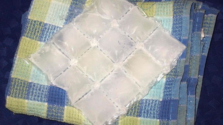 Ein Eisw&uuml;rfelpack liegt auf einer karierten Decke, ideal zum K&uuml;hlen von H&auml;morrhoiden zur Linderung von Beschwerden.