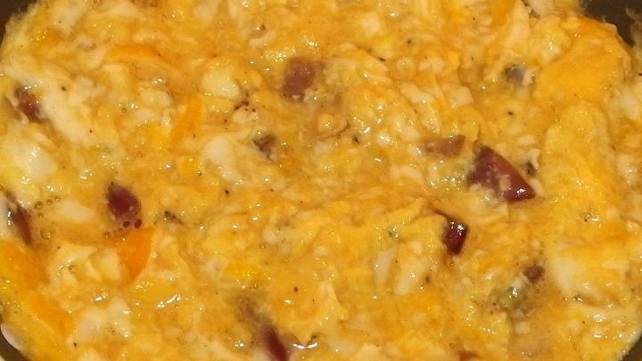 Ein schaumiges R&uuml;hrei wird in einer Pfanne zubereitet, umgeben von einer warmen K&uuml;chenszene.