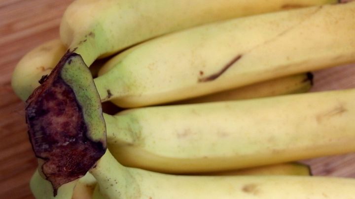 Reife Bananen liegen zusammen, bereit zum Backen, auf einer Holzoberfl&auml;che in einer gem&uuml;tlichen K&uuml;chenszene.