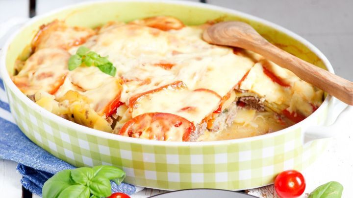 Ein herzhaftes Hackfleisch-Kartoffel-Auflauf wird serviert, w&auml;hrend er in einer gr&uuml;n-wei&szlig; karierten Auflaufform dampft.