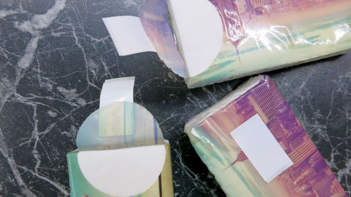 Tempo-Taschentuch-Verpackungen mit wei&szlig;en Verschl&uuml;ssen liegen auf einer dunklen Oberfl&auml;che als kreative Lesezeichen.