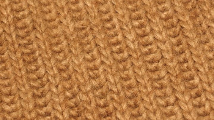 Ein weiches, goldbraunes Strickmaterial liegt auf einer Fl&auml;che, bereit zum Waschen empfindlicher Kleidung.