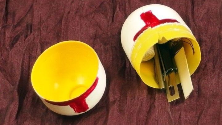 Ein farbenfrohes D&ouml;schen ist ge&ouml;ffnet, zeigt Inhalt und steht auf einem weichen, braunen Untergrund.