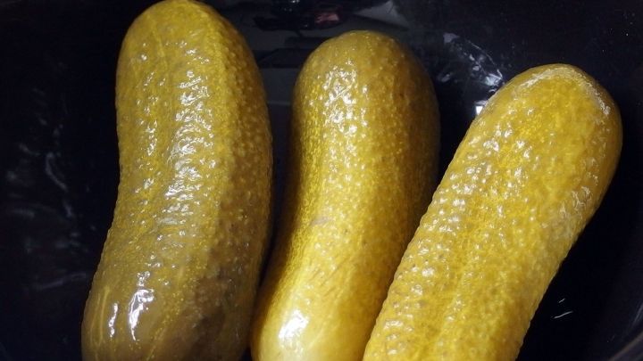 Saure Gurken schwimmen in einer Sch&uuml;ssel, gl&auml;nzend und frisch, ideal gegen Appetitlosigkeit in einer s&uuml;&szlig;en Sauermarinade.