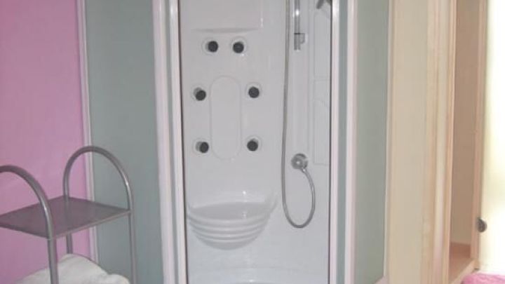 Eine moderne Duschkabine steht in einem rosa gef&auml;rbten Badezimmer, bereit f&uuml;r die Nutzung und zur Vermeidung von Kalkflecken.