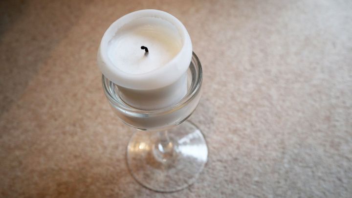Ein Glaskerzenst&auml;nder mit einer wei&szlig;en Kerze steht auf einem hellen Untergrund, bereit zum Anz&uuml;nden.