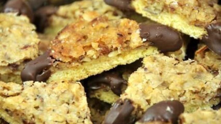 Nussecken mit Schoko&uuml;berzug liegen gestapelt, ihre knusprige Nussf&uuml;llung sichtbar, in einem Backblech.