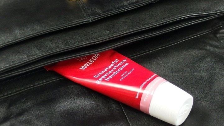 Ein Haarpflegeprodukt befindet sich in einer offenen schwarzen Handtasche, bereit zur Anwendung f&uuml;r unterwegs.