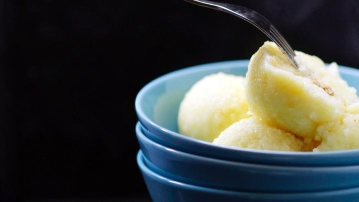 Eine Hand mit einer Gabel greift in eine Sch&uuml;ssel gef&uuml;llte Kl&ouml;&szlig;e, die dampfend serviert sind.