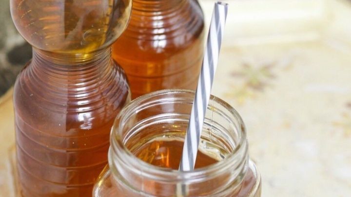 Drei Wasserflaschen stehen neben einem Glas mit Strohhalm, das in einer gem&uuml;tlichen Umgebung auf einem Tablett platziert ist.