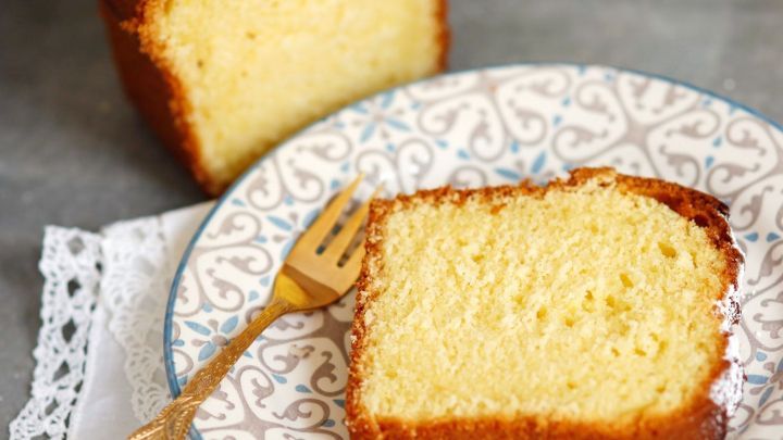 Ein saftiges St&uuml;ck Sch&uuml;ttelkuchen liegt auf einem eleganten Teller, neben einem gr&ouml;&szlig;eren Kuchen, auf einem dekorierten Tisch.