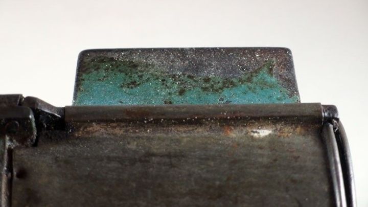 Ein metallisches Objekt mit Gr&uuml;nspan zeigt eine Reaktion, w&auml;hrend Salmiakgeist zur Reinigung verwendet wird.