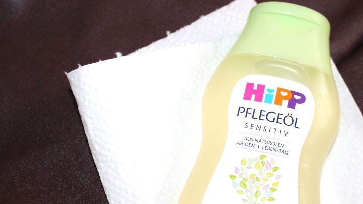 Ein Baby&ouml;lflasche steht neben einem Papiertuch auf einem Glattledersofa, bereit, Flecken zu entfernen.