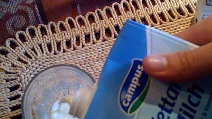 Milch wird aus einem blauen Karton in ein Glas auf einer Tischdecke gegossen, ohne dass es spritzt. Text: "H-fettarme Milch".