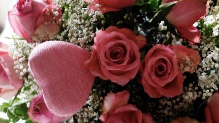 Ein Strau&szlig; frischer Rosen steht im Vordergrund und wird von zarten Bl&auml;ttern umrahmt, ideal f&uuml;r eine Pr&auml;sentation.