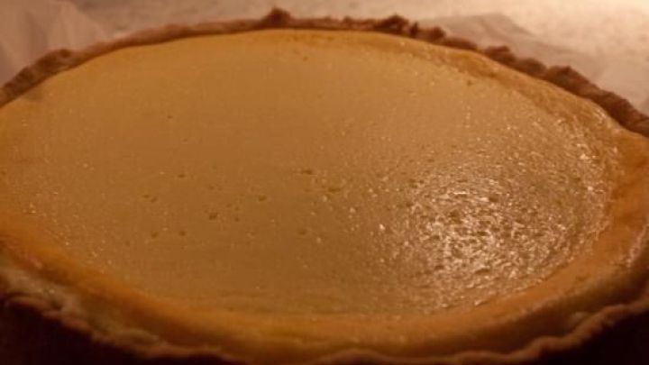 Ein goldbrauner Allg&auml;uer K&auml;sekuchen liegt frisch gebacken auf einem Backblech in einer warm beleuchteten K&uuml;che.