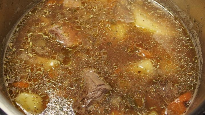 Eine k&ouml;stliche Fleischsuppe kocht in einem Topf, mit zarten Fleischst&uuml;cken und Gem&uuml;se in einer wohligen Br&uuml;he.