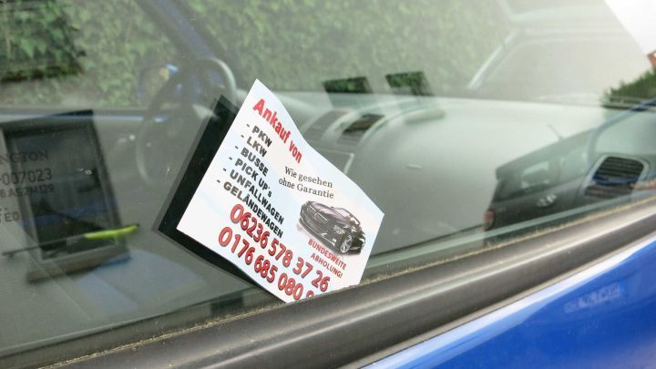 Ein Verkaufsangebot ist auf einem Auto sichtbar angebracht. Es steht auf einem Zettel im Fenster und enth&auml;lt Kontaktinformationen.