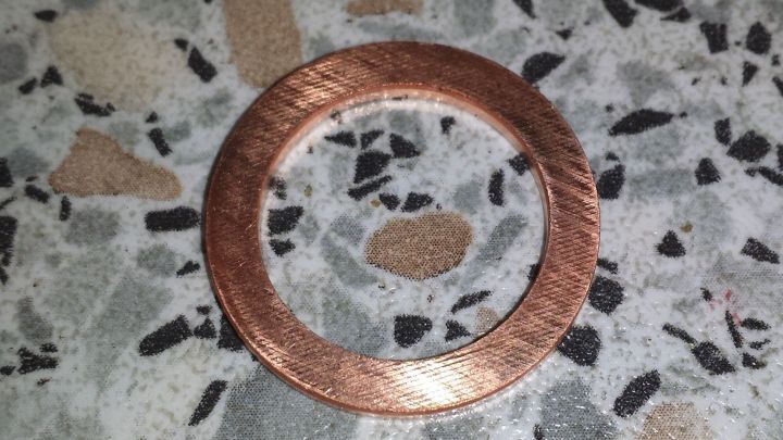 Ein Kupferring liegt auf einer strukturierten Oberfl&auml;che und ist sauber, was auf eine Reinigung mit Ketchup hindeutet.