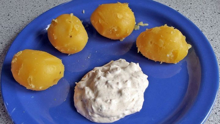 Auf einem blauen Teller liegen vier gekochte Kartoffeln neben einem Klecks Super Kr&auml;uterquark.