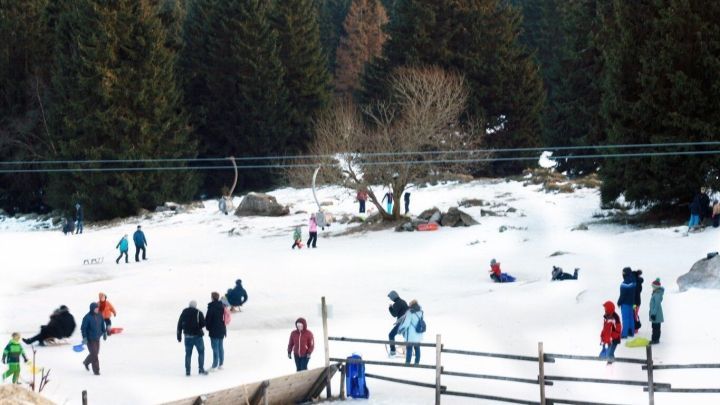Kinder spielen fr&ouml;hlich im Schnee, w&auml;hrend sie warme Schuhe tragen, um sich bei Wind und Wetter drau&szlig;en zu bewegen.