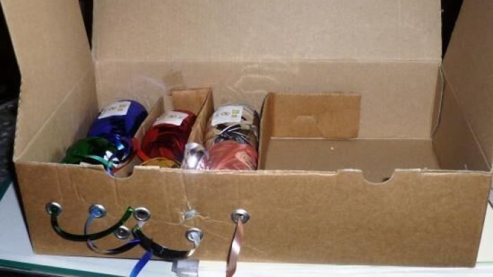 Ein leerer Kartoffelchips-Beh&auml;lter dient als Aufbewahrung f&uuml;r Geschenkb&auml;nder, die ordentlich verstaut sind, auf einem Tisch.