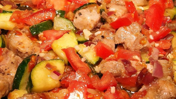 Zarte, geschnetzelte Fleischst&uuml;cke liegen auf einer bunten Mischung aus frischem Gem&uuml;se in einer Sch&uuml;ssel.