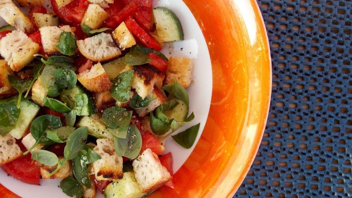 Ein farbenfroher Brotsalat mit Wei&szlig;brotresten, Mix aus Tomaten, Gurken und frischem Gem&uuml;se auf einem wei&szlig;en Teller.